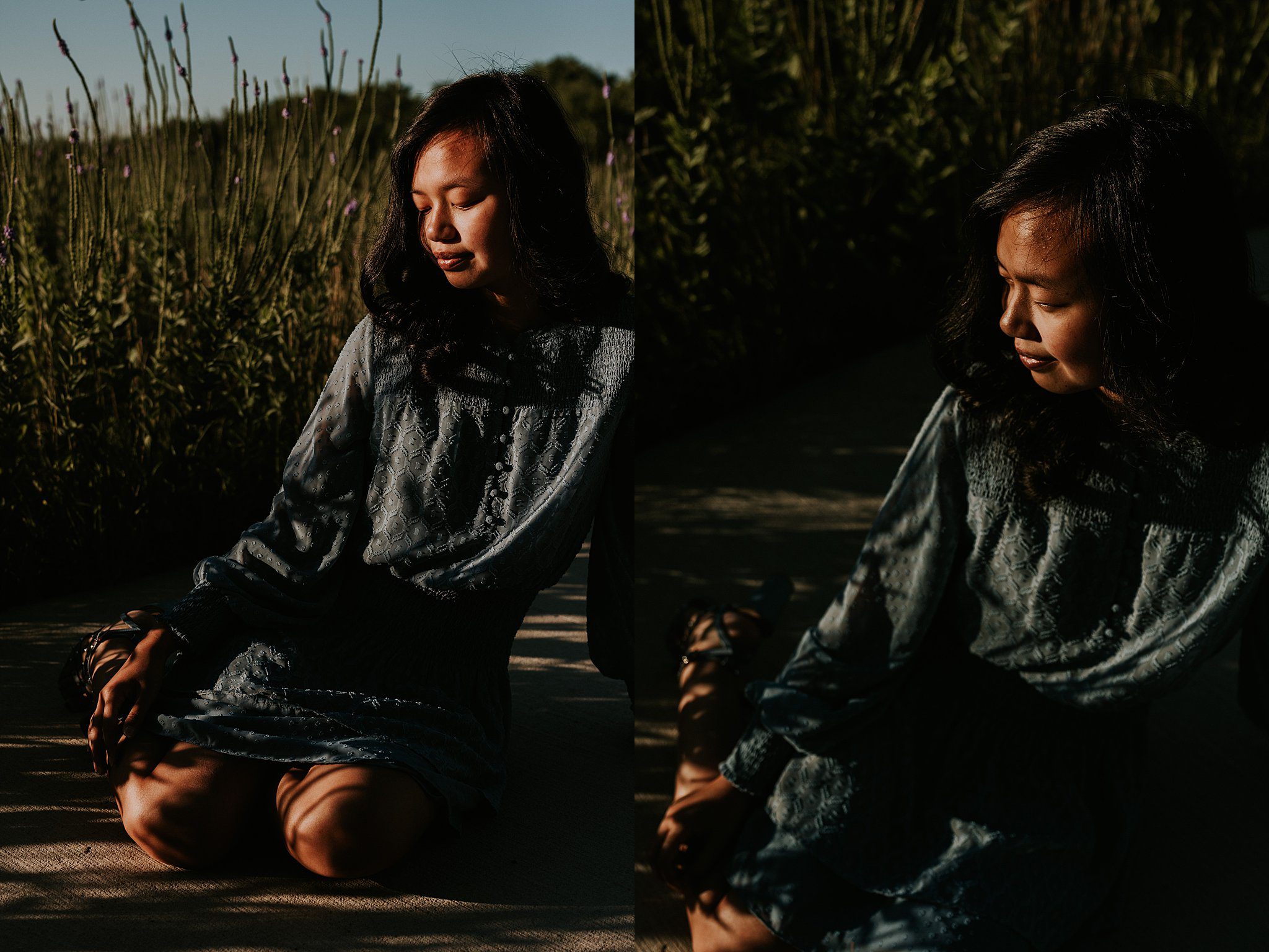 A girl is sitting getting her senior portraits taken next to some purple flowers. The direct sun highlights her face and blue dress as she looks down at the ground.